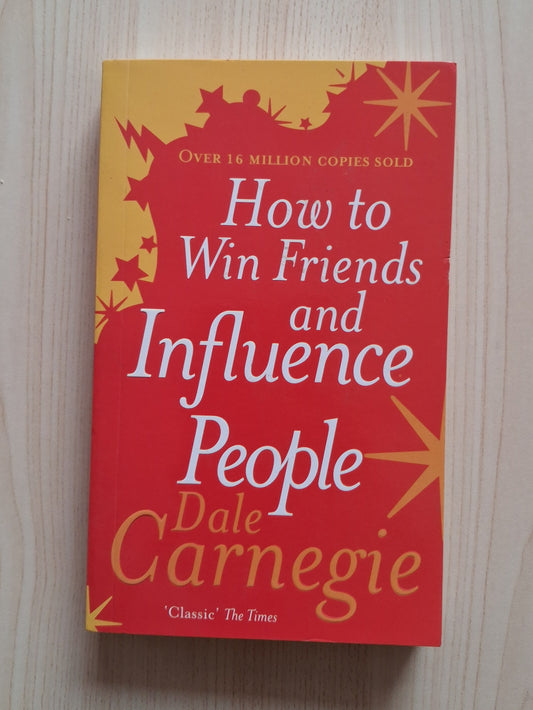 Book titled 'How to Win Friends and Influence People' by Dale Carnegie on a wooden surface