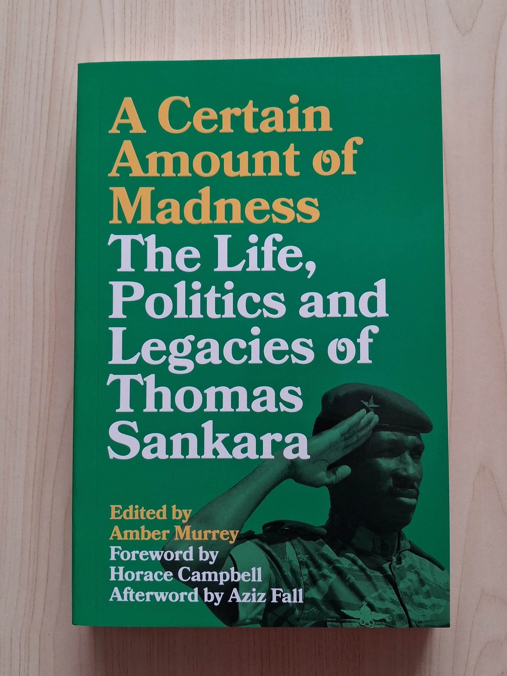 Book titled 'A Certain Amount of Madness: The Life, Politics and Legacies of Thomas Sankara' on a wooden surface
